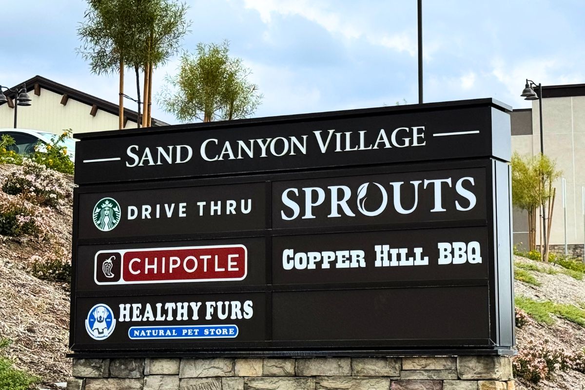The Sign in front of the Sand Canyon Village Retail Center showing options like Starbucks, Sprouts, Chipotle, and Copper Hill BBQ.