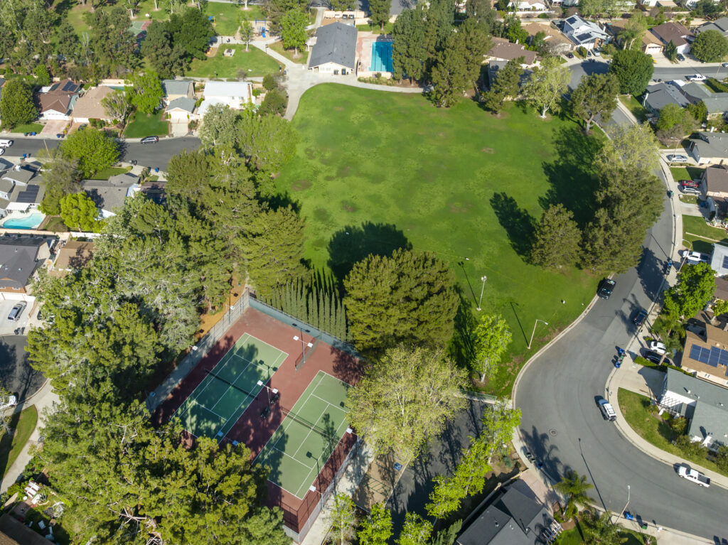 Aerial view of the lush green Valencia Glen Park and the shaded tennis courts