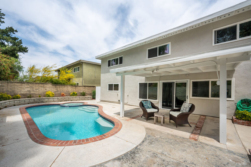 A spacious backyard in the Valencia North neighborhood with a pool and covered patio.